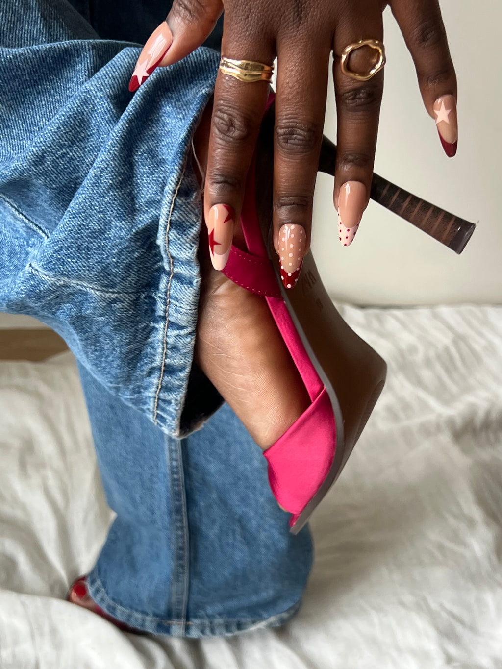 Press-on nails Icon Cherry nude et rouge avec détails étoile et french graphique portés avec jean et talons roses