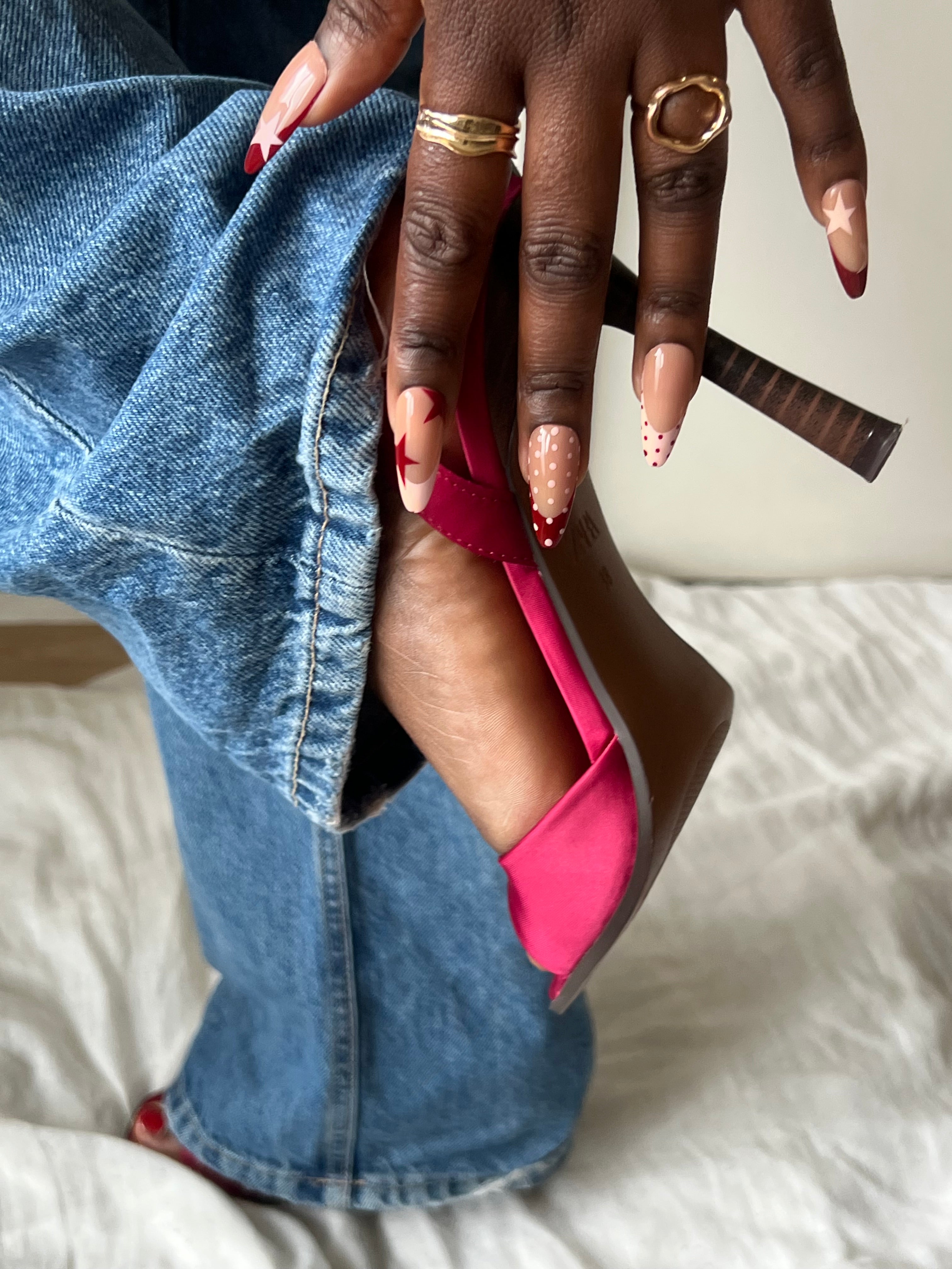 Press-on nails Icon Cherry nude et rouge avec détails étoile et french graphique portés avec jean et talons roses